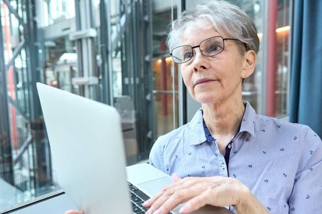 Germany - September 4, 2025: An experienced senior citizen works intently on her laptop at the company. The image shows how active retirement and working until 70 open up new opportunities in retirement.