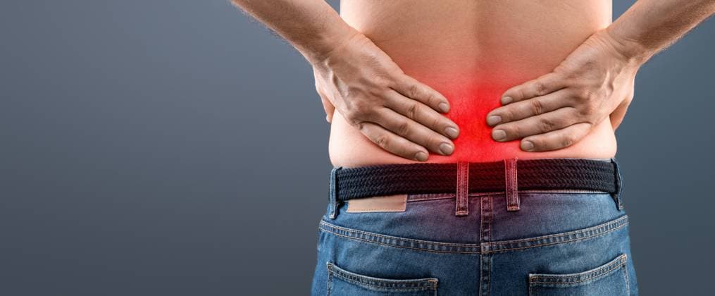 Closeup of unrecognizable man rubbing his low back Closeup of unrecognizable man in jeans rubbing his low back, having pain, sore zone highlighted with red, grey studiio background. Backache, rheumatism, osteochondrosis, radiculitis concept, model released, , 96150822.jpg RECORD DATE NOT STATED