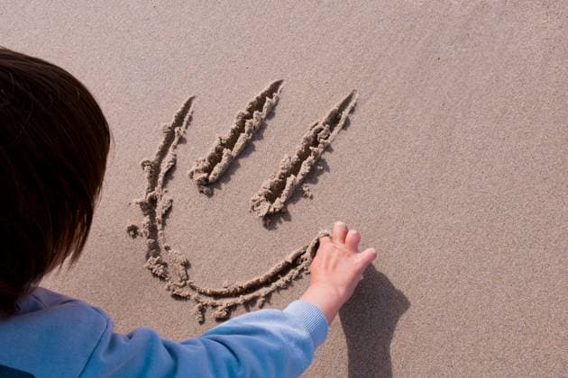 Child drawing smiley face in sand. Fun beach activity Child drawing smiley face in sand. Fun beach activity., model released, , 96386434.jpg RECORD DATE NOT STATED