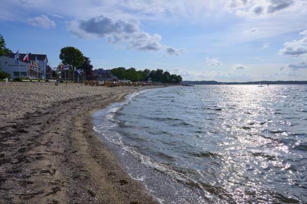 Sandstrand mit welligem Meer unter blauem Himmel, die Sonne reflektiert auf dem Wasser, Heikendorf, Kreis Plön, Kieler Förde, Schleswig-Holstein Sandy beach beach with undulating sea under a blue sky, the sun reflected on the water, Heikendorf, Plön district, Kiel Fjord, Schleswig-Holstein Copyright: imageBROKER RaimundxLinke ibxrde15149785.jpg