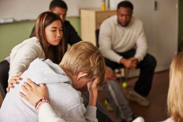 Teenage girls consoling sad male friend during group therapy session at junior high school Sweden, Stockholm, model released, property released Copyright: xMaskotx , MA120470 MA120470