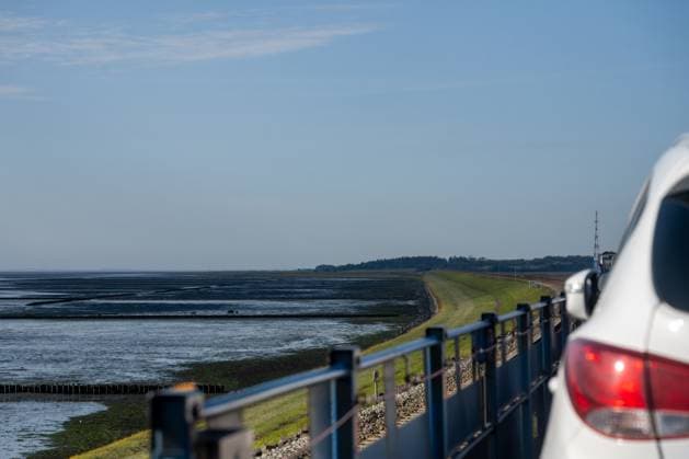 Journey to the island of Sylt View from the car transporter on the Hindenburgdamm in the direction of the island of Sylt in a left-hand bend at low tide A car cut off on the right-hand edge Nordfriesland Schleswig Holstein Germany