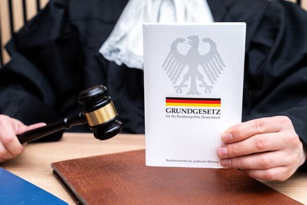 Bavaria, Germany - October 8, 2025: A judge holds the Basic Law of the Federal Republic of Germany in his hand. The symbolic photo stands for the rule of law, the constitution, democracy and the importance of the Basic Law in the Federal Republic of Germany