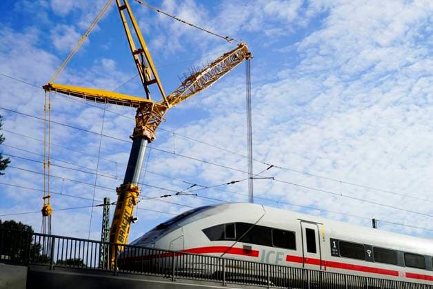 CNTV BAHNSANIERUNG Brueckenarbeiten DB Bahn workers work with protective clothing while rail traffic is running ICE with excavator crane on new tracks, laying bridge parts rails and concrete sleepers Construction work on the line between Hamburg and Berlin is proceeding according to plan Hamburg October 2025 Hamburg Germany