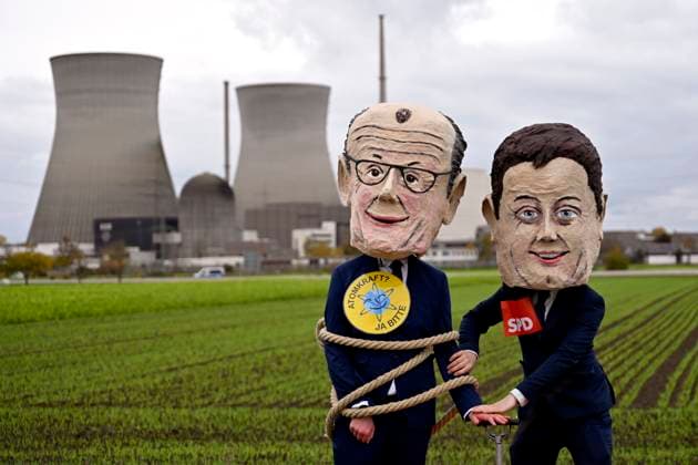 The cooling towers of the nuclear power plant in Gundremmingen before the demolition Demonstrators wearing masks of Federal Chancellor Friedrich Merz CDU and politician Lars Klingbeil SPD pose an Copyright: xDwixAnoraganingrumx
