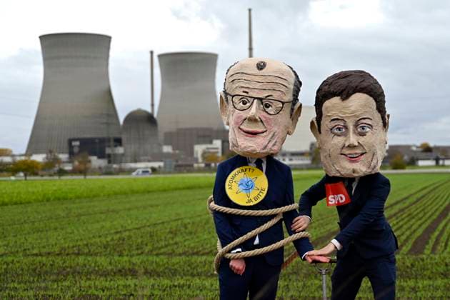 The cooling towers of the nuclear power plant in Gundremmingen before the demolition Demonstrators wearing masks of Federal Chancellor Friedrich Merz CDU and politician Lars Klingbeil SPD pose an Copyright: xDwixAnoraganingrumx