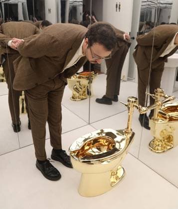 November 7, 2025, New York, New York, USA: A man examines Maurizio CattelanÃ¢â‚¬â ¢s America (2016): a fully functional toilet made from just over 100 kilograms of solid 18-karat gold, estimate starting at $10 million, seen on display during November Marquee Week 2025 during SothebyÃ¢â‚¬â ¢s Opening of the New Global Headquarters at the Breuer. New York USA - ZUMAk03_ 20251107_zaf_k03_008 Copyright: xNancyxKaszermanx