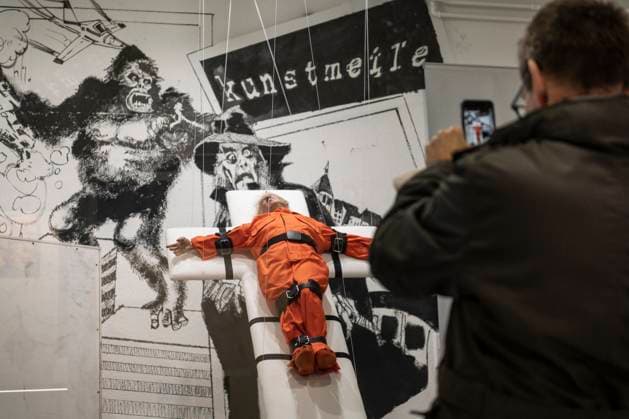 November 8, 2025, Basel, Basel-Stadt, Switzerland: A man takes a picture to a sculpture depicting the US President Donald Trump in a prisoner orange jumpsuit and strapped to a cross looking like a death row strapped-down bed, is displayed in a gallery of the city centre of Basel, Switzerland Basel Switzerland - ZUMAp199 20251108_zip_p199_004 Copyright: xMatteoxPlacuccix