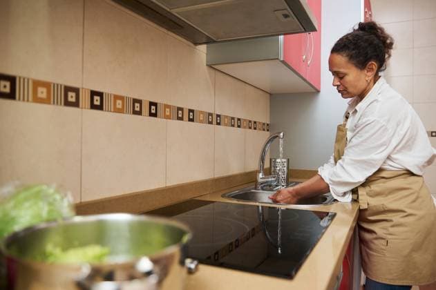 Woman in kitchen washing hands before cooking with vegetables Woman washes hands in a modern kitchen before preparing a meal with fresh vegetables, demonstrating hygiene and healthy cooking practices., model released, , property released, , 62816684.jpg RECORD DATE NOT STATED