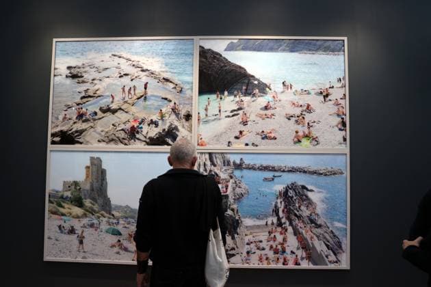 A visitor to the 2025 Paris Photo Fair stands before images by Italian artist Massimo Vitali of Zander Gallery on the opening day at the Grand Palais, on Wednesday, November 12, 2025. The world s most important international photography fair brings together iconic and emerging names, showcasing 179 galleries from 33 countries and a rich programme that encompasses photography in all its forms, from silver gelatin to blockchain.  PAR20251112103 MAYAxVIDON-WHITE