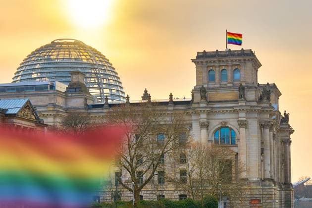 Bavaria, Germany - November 16, 2025: PHOTOMONTAGE, A rainbow flag flies in front of the German Bundestag, symbolizing LGBTQ rights, diversity, and equality. The image combines political debates with the commitment to acceptance and social openness.