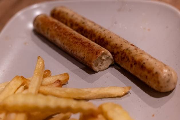 Vegan sausages with fries on plate 16 11 25, Selters Symbol photo, illustration picture, symbol image, illustration photo, everyday scene On a plate are two fried vegan sausages, one of which is already bitten into In the foreground are French fries The photo shows a served, simple meal with plant-based meat substitute and side dish S Copyright: xThorstenxWagnerx