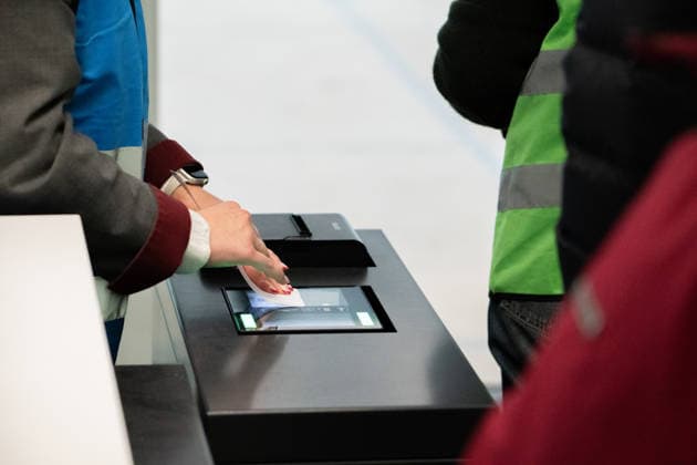 Munich, Bavaria, Germany - November 25, 2025: An employee scans a boarding pass at the counter at Munich Airport while ground staff prepare for the boarding process. Trial operation for the new boarding gate in Terminal 1 at Munich Airport. Volunteers test processes ahead of the planned opening in 2026