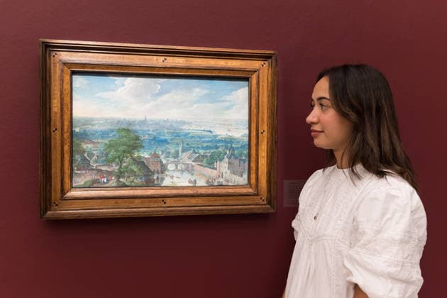 November 28, 2025, London, England, United Kingdom: A staff member looks at a painting titled Panoramic landscape with a tower and a river in the foreground and a view of Antwerp and the River Schelde in the distance by Hans Bol, estimate: 600,000 - 800,000 GBP during a photocall at Sotheby s auction house ahead of Old Master & 19th Century Paintings Sales. London United Kingdom - ZUMAs371 20251128_zip_s371_016 Copyright: xWiktorxSzymanowiczx