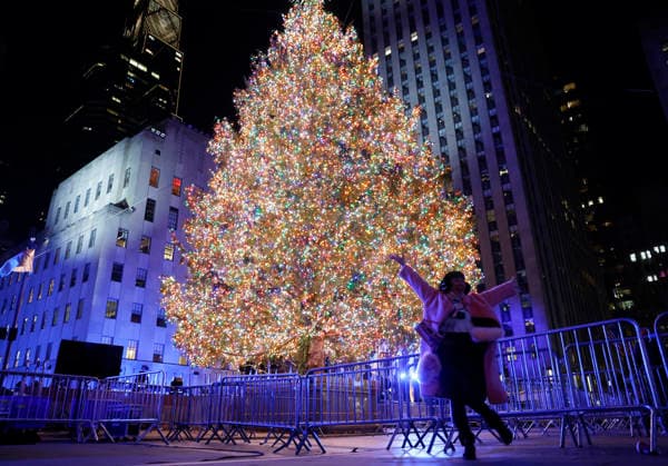 A reveler poses for a photograph with the Rockefeller Center Christmas Tree after it is lit for the first time of the season at the 93rd annual Rockefeller Center Christmas Tree lighting ceremony takes place in New York City on Wednesday, December 3, 2025. The 75-foot-tall Norway Spruce came from a home in East Greenbush, New York.  NYP20251203120 JOHNxANGELILLO