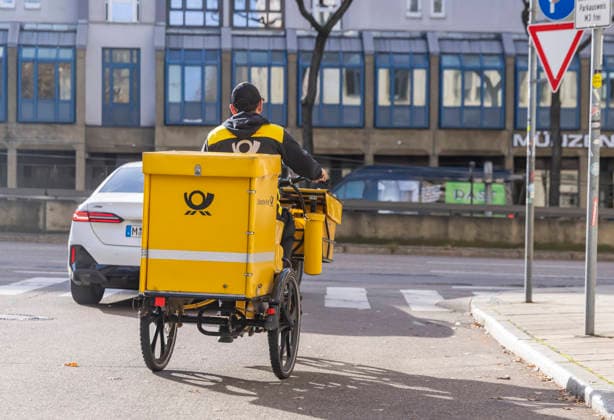 Deutsche Post letter carrier riding his bicycle 17 11 2025 Stuttgart, Baden Württemberg, Germany