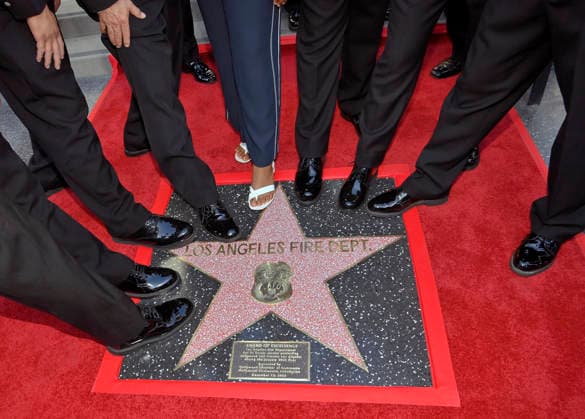 Firefighters participate in an unveiling ceremony honoring the Los Angeles Fire Department with an Award of Excellence star adjacent to the Hollywood Walk of Fame in Los Angeles on Tuesday, December 2, 2025. EniolaTaiwo, 14, wrote a letter to the Hollywood Chamber of Commerce suggesting that firefighters who battled the deadly January fires were worthy of a star on the Hollywood Walk of Fame. The letter precipitated the tribute.  LAP2025121209 JIMxRUYMEN