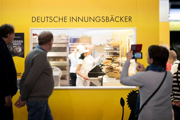 Gruene Woche Berlin DEU, Deutschland, Germany, Berlin, 23.01.2026 Besucher vor Logo Erlebnis Bauernhof Ernaehrung sichern Natur Schuetzen zum Thema Innungsbaecker Ernaehrungssicherheit und oekologische Landwirtschaft in der Biohalle vom Forum Moderne Landwirtschaft auf der Messe der Internationalen Gruenen Woche unter dem Motto Tradition trifft Zukunftsvisionen Gutes Essen Starkes Land Zukunftsfeste Landwirtschaft 100 Jahre 1926 - 2026 in Berlin Deutschland . Die Internationale Gruene Woche Berlin ist eine internationale Verbrauchermesse und Ausstellung der Ernaehrungswirtschaft Landwirtschaft Gartenbau und fuer landwirtschaftliche Produkte aus aller Welt. Die Messe gibt aktuellen gesellschaftlichen Fragen wie Klimaschutz Kreislaufwirtschaf