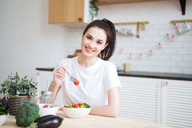 Lächelnde junge Frau, die einen biologischen vegetarischen Salat isst, während sie zu Hause in der Küche sitzt. smiling young woman eating organic vegetarian salad sitting in the kitchen at home . (License=RF) ,model released, Symbolfoto Copyright: xZoonar.com UliaxZotaninax 24514182 ,model released, Symbolfoto ,property released
