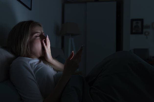 Schläfrige, müde Frau liegt im Bett, benutzt ihr Smartphone, bedeckt ihren Mund mit der Hand und gähnt. Schlaflosigkeit Young sleepy tired woman lying in bed, using smartphone, covering mouth with hand and yawning, eyes closed, can not sleep, Insomnia, nomophobia, sleep disorder. Social networks addict concept. (License=RF) ,model released, Symbolfoto Copyright: xZoonar.com DmitriixMarchenkox xEnvatox 24568791 ,model released, Symbolfoto ,property released