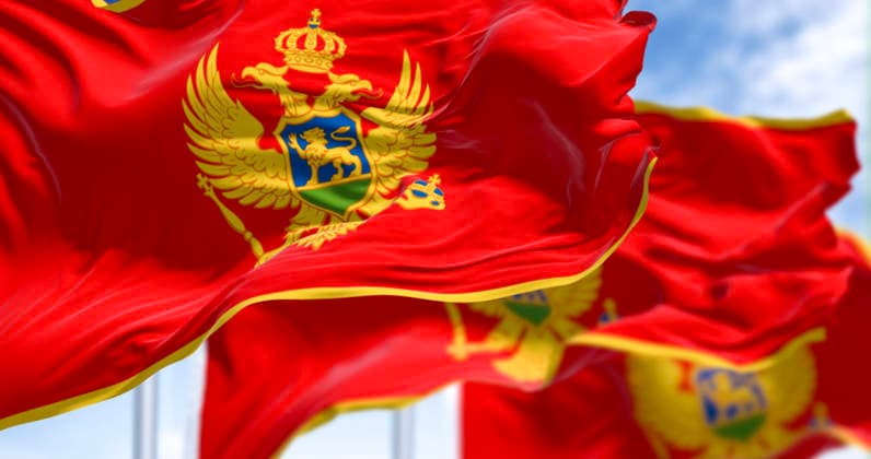Nationalflaggen von Montenegro wehen an einem klaren Tag im Wind National flags of Montenegro waving in the wind on a clear day. Red with a golden border and features the national coat of arms in its center. 3d illustration render. Selective focus. Fluttering fabric (License=RF) Copyright: xZoonar.com ValerioxRosatix 24651904