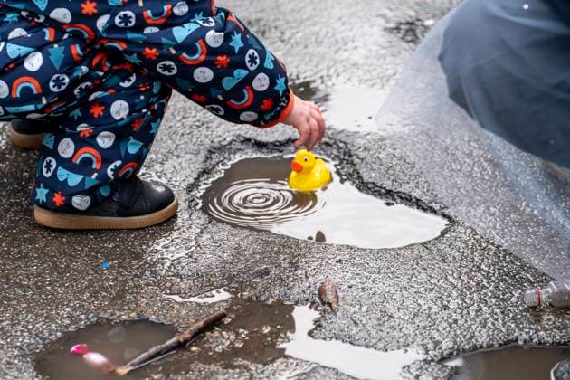 Rose Monday parade in Düsseldorf, participants in the parade, child playing with plastic ducklings it caught as camels during the parade, getting ready for the rain, at the street carnival, in heavy rain, NRW, Germany Rose Monday DUS