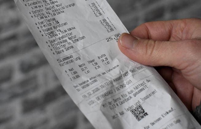 A woman holds a receipt in her hand after shopping Life in Germany has become noticeably more expensive