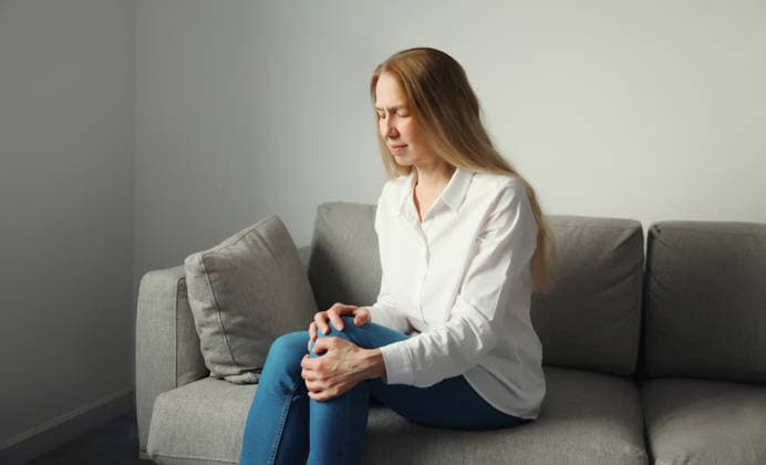 Frau leidet zu Hause unter Schmerzen im Knie und im Bein. Health care concept. Mature woman suffering from pain in knee rubbing leg sitting on couch at home. Old age, health problem and people concept (License=RF) ,model released, Symbolfoto Copyright: xZoonar.com VeronikaxKornevax 24750756 ,model released, Symbolfoto ,property released