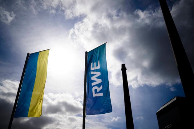 Feature, flag of RWE AG on the RWE Campus, Ukrainian flag, UKR, logo, sky, sun, lettering, behind it the heating plant Essen city center balance sheet press conference of RWE AG, on 12 03 2026 in Essen Germany @ RWE Campus
