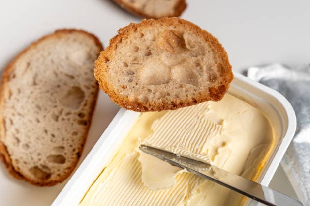 Bavaria, Germany March 31, 2026: Butter or margarine is spread on bread with a knife, depicting a typical everyday breakfast scene in which simple foods, consumption, and routines play a central role in daily life and nutrition.