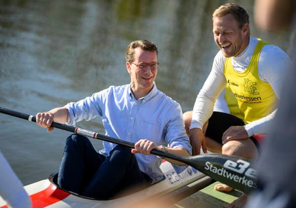 Minister President Hendrik Wüst NRW sits in a rowing boat and holds an oar in his hand, next to canoe Olympic champion Max Rendschmidt r Minister President Hendrik Wüst NRW visits the Federal Canoeing Performance Center, on 07 04 2026 in Duisburg Germany Federal Canoeing Performance Center