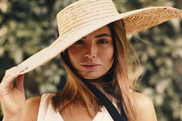 Porträt einer jungen stilvollen Frau, die ihren Strohhut hält, während sie vor einer grünen Wand steht Portrait of young stylish woman holding her straw hat while standing in front of a green wall Copyright: imageBROKER ArtemxVarnitsin ibxiqx17151936.jpg ,model released, Symbolfoto ,property released