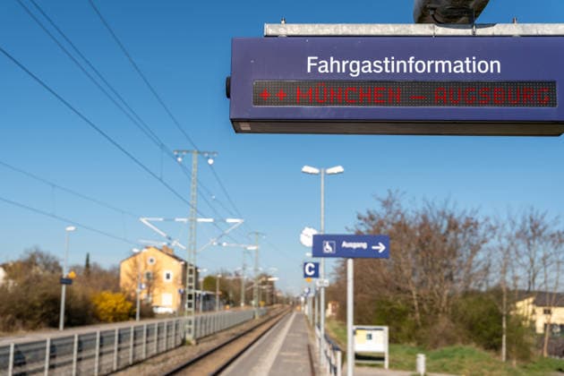 Germany - April 9, 2026: PHOTOMONTAGE, digital passenger information display at the train station showing Munich Augsburg. The image depicts a major commuter route in Bavaria and symbolizes frequent train service as well as potential disruptions in regional rail traffic.