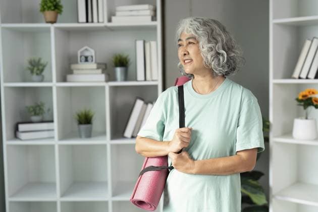 Lächelnde Seniorin mit Yogamatte, die einen gesunden Lebensstil und Bewegungsbereitschaft in einer stilvollen Innenumgebung verkörpert Smiling senior woman carrying a yoga mat, embodying a healthy lifestyle and readiness for exercise in a stylish indoor environment Copyright: imageBROKER WORAWEExMEEPIAN ibxiqx17169950.jpg ,model released, Symbolfoto ,property released