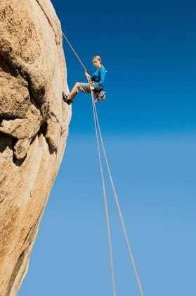 Woman Rappelling From Cliff - Low angle view of a young woman rappelling from cliff against clear blue sky model released Symbolfoto Copyright: xmoodboardx Panthermedia75337746.jpg