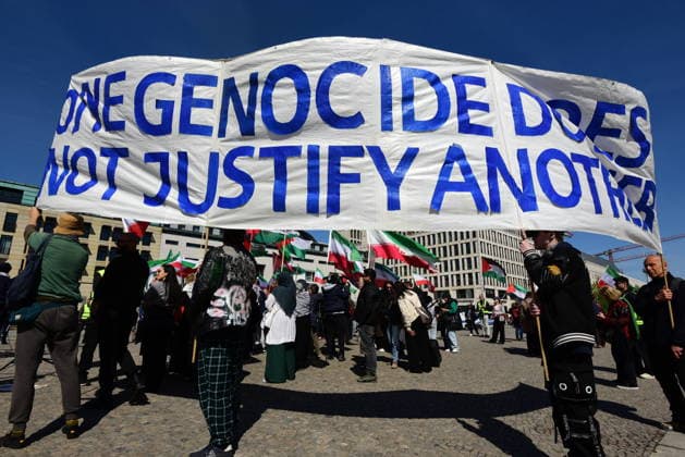 Opponents of Reza Pahlavi protest against Pahlavis visit at Pariser Platz at the Brandenburg Gate Banner with the inscription One genocide does not justify another Supporters of Pahlavi protest against Reza Pahlavi gathered in front of the Reichstag at the same time