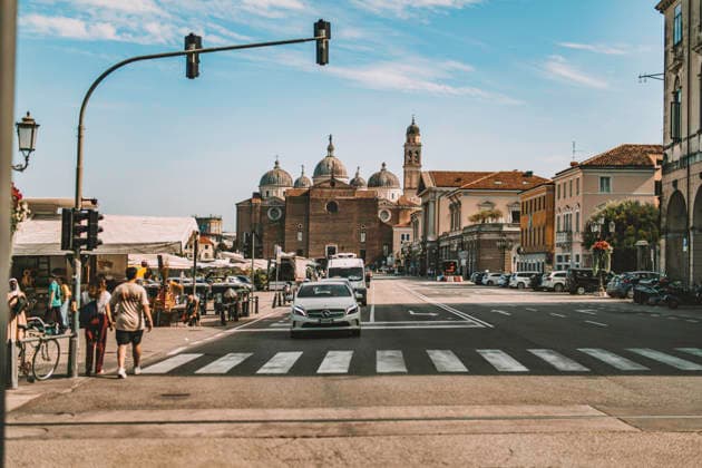 Padova, italy 1 october 2025: people crossing a busy padua street with cars and the historic basilica di sant antonio rising behind, sunny urban summer scene Padua city street life with historic basilica Copyright: xx 0835