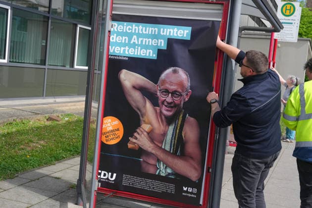 Protest posters against the CDU on the fringes of the CDA federal conference Employees of the city of Marburg remove arbitrarily placed protest posters against Chancellor Merz and the CDU at a bus stop opposite the event hall for the 41st federal conference of the CDA in Marburg, 25 04 2026 Marburg Hessen Germany