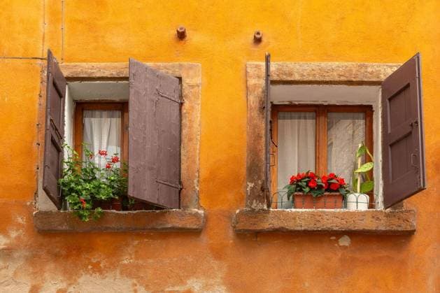 Two old windows with wooden shutters and flower pots on orange facade in Verona, Italy. Copyright: xkavalenkavax Panthermedia102593970.jpg