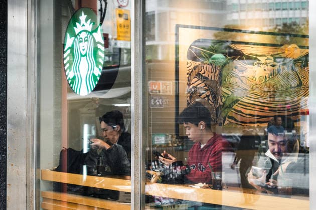 Starbucks schließt in Südkorea temporär alle Filialen, Archivbilder Seoul, South Korea April 28, 2026: Visitors sit in a Starbucks branch and use their smartphones; the cafÃ serves as a place for breaks and everyday leisure