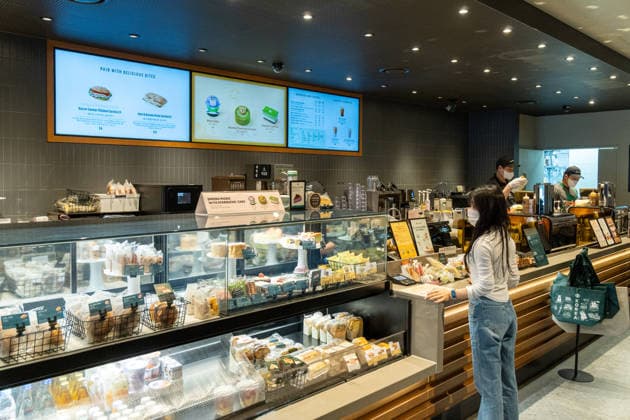 Starbucks schließt in Südkorea temporär alle Filialen, Archivbilder Seoul, South Korea April 28, 2026: A customer places an order at the counter of a Starbucks location, while baked goods and snacks are displayed behind the glass display case and baristas prepare drinks