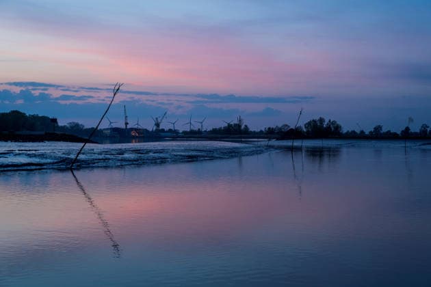 Germany, Schleswig Holstein, Borsfleth, 02 05 2025 The sun sets over the Stör near Borsfleth Schleswig Holstein In the background you can see the shipyard of Wewelsfleth with its cranes Sunset over the Stör
