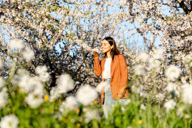 Smiling model smelling blooming tree in spring orchard in Spain model released, Symbolfoto, YPF00251
