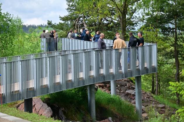 Neue Aussichtsplattform am Schacht 371 eröffnet Wismut macht Bergbaugeschichte erlebbar Die Wismut GmbH hat heute am traditionsreichen Schacht 371 bei Hartenstein eine neue Aussichtsplattform eröffnet und damit einen weiteren öffentlich zugänglichen Ort geschaffen, an dem die Geschichte des Uranerzbergbaus im Westerzgebirge sichtbar und erfahrbar wird. Im Bild: Zugang zur Aussicht. Der Standort zählt zu den bedeutendsten Anlagen des ehemaligen SDAG Wismut Bergbaus. Der Schacht war bis zu seiner Stilllegung 1991 das tiefste Bergwerk Deutschlands. Die neue Plattform bietet einen freien Blick auf das weitläufige Areal des Schachtes, auf markante Relikte der Bergbauinfrastruktur sowie auf die landschaftlich reizvolle Umgebung zwische Aue-Bad-Schlema_Wismut_025-0605-26
