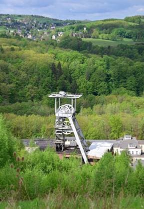 Neue Aussichtsplattform am Schacht 371 eröffnet Wismut macht Bergbaugeschichte erlebbar Neue Aussichtsplattform am Schacht 371 eröffnet Wismut macht Bergbaugeschichte erlebbar Die Wismut GmbH hat heute am traditionsreichen Schacht 371 bei Hartenstein eine neue Aussichtsplattform eröffnet und damit einen weiteren öffentlich zugänglichen Ort geschaffen, an dem die Geschichte des Uranerzbergbaus im Westerzgebirge sichtbar und erfahrbar wird. Im Bild: Blick auf die Übertageanlagenmit dem Fördergerüst. Der Standort zählt zu den bedeutendsten Anlagen des ehemaligen SDAG Wismut Bergbaus. Der Schacht war bis zu seiner Stilllegung 1991 das tiefste Bergwerk Deutschlands. Die neue Plattform bietet einen freien Blick auf Aue-Bad-Schlema_Wismut_028-0605-26