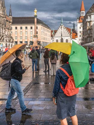 Nach Wolkenbruch und Gewitter blinzelt schon wieder die Sonne durch eine Wolkenlücke und taucht den Marienplatz in ein wunderbares Licht, Passanten mit bunten Regenschirmen, München, 6. Mai 2026 Deutschland, München, 6. Mai 2026, nach Wolkenbruch scheint schon wieder die Sonne über dem Marienplatz, Passanten mit bunten Regenschirmen, zuvor heftiger Starkregen mit Gewitter, Mitwocnachmittag um 17:30 Uhr, Innenstadt, Wirtschaft, Wetter, Unwetter, Frühling, Bayern