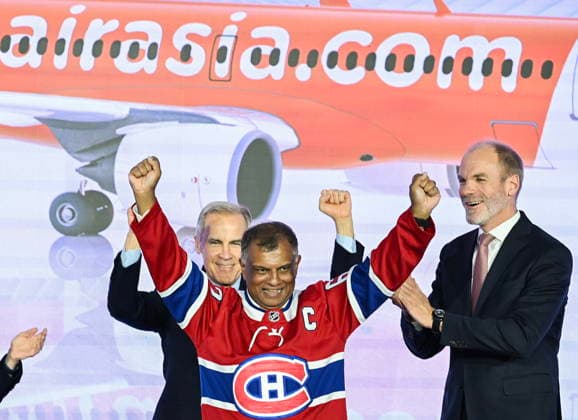 May 6, 2026, Mirabel, Pq, Canada: Prime Minister Mark Carney, left, and Lars Wagner, CEO, Airbus Commercial Aircraft, right, cheer on AirAsia CEO Tony Fernandes, centre, during an event at the Airbus A220 Delivery Center in Mirabel, Que., Wednesday, May 6, 2026, where AirAsia placed a landmark order for 150 Airbus A220 aircraft. Mirabel Canada - ZUMAc35_ 20260506_zaf_c35_132 Copyright: xGrahamxHughesx