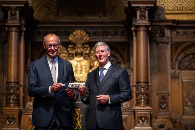 Friedrich Merz, Federal Chancellor, after his speech at Hamburg City Hall, with Harald Vogelsang, President of the Overseas Club and Chairman of the Board of Hamburger Sparkasse, at the presentation of a ship in a bottle as a traditional gift 76 Great Overseas Day in Hamburg, April 2026 Ceremony at Hamburg City Hall, Hamburg Hamburg Germany City Hall