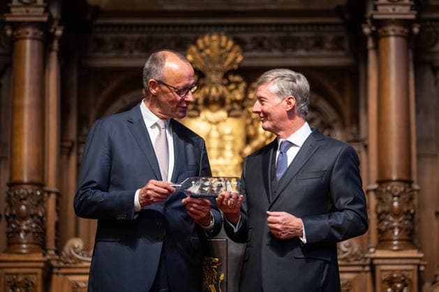 Friedrich Merz, Federal Chancellor, after his speech at Hamburg City Hall, with Harald Vogelsang, President of the Overseas Club and Chairman of the Board of Hamburger Sparkasse, at the presentation of a ship in a bottle as a traditional gift 76 Great Overseas Day in Hamburg, April 2026 Ceremony at Hamburg City Hall, Hamburg Hamburg Germany City Hall