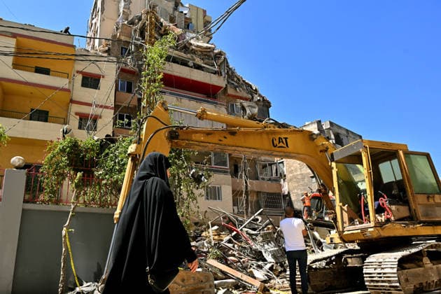 May 7, 2026, Beirut, Beirut, Lebanon: A Lebanese resident of Beirut southern suburb walks past civil defense members clearing rubble from the site of a building destroyed by an Israeli air raid in the bastion of pro-Iranian Hezbollah. Israel confirmed it killed Ahmed Ghaleb Ballout, a commander in HezbollahÃ¢â‚¬â ¢s elite Radwan Force in the attack. Beirut Lebanon  - ZUMAn313 20260507_zip_n313_005 Copyright: xMarwanxNaamanix
